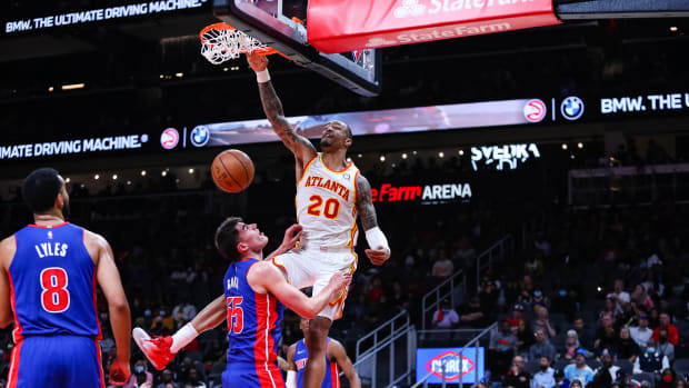 John Collins dunks over Detroit Pistons defnders.